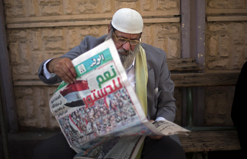 An Egyptian man reads a local newspaper which has a main headline in Arabic that reads,"yes to the constitution," while he waits his turn to cast his vote in the country's constitutional referendum in Cairo, Egypt, Tuesday, Jan. 14, 2014. Upbeat and resentful of the Muslim Brotherhood, Egyptians voted Tuesday on a new constitution in a referendum that will pave the way for a likely presidential run by the nation's top general months after he ousted Islamist President Mohammed Morsi. (AP Photo/Khalil Hamra)