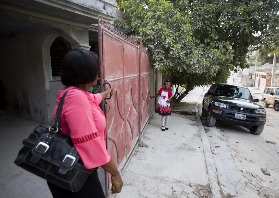 Franchina 11, helps her foster mother, Nelia Pierre, close the gate to their home in Port-au-Prince, Haiti as they head to church on Sunday, July 1, 2018. Over the years, the Pierres have provided a temporary home to other children on an informal basis. (AP Photo/Dieu Nalio Chery)