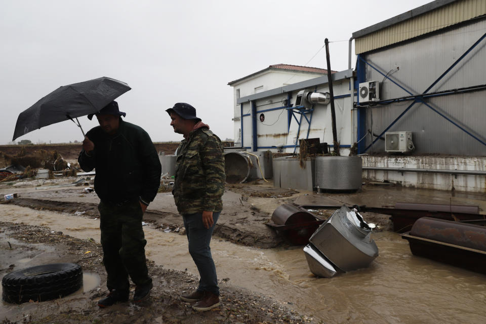 Two men stand outside a damaged business after a rainstorm, in Nea Lefki village, near Larissa, central Greece, Wednesday, Sept. 6, 2023. Severe rainstorms that lashed parts of Greece, Turkey and Bulgaria have caused several deaths as rescuers continue searching for missing people. (AP Photo/Vaggelis Kousioras)