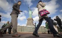 People walk past the Statue of Liberty on Liberty Island in New York, October 13, 2013. REUTERS/Carlo Allegri