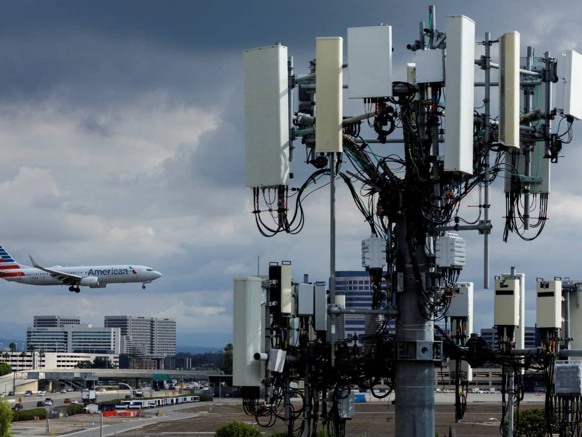Dubai-based Emirates announced it would halt flights to Boston, Chicago, Dallas-Fort Worth, Houston, Miami, Newark, New Jersey, Orlando, San Francisco and Seattle. Above, a cellphone tower is seen as a plane approaches to land at John Wayne Airport in Santa Ana, Calif., on Tuesday.  (Mike Blake/Reuters - image credit)