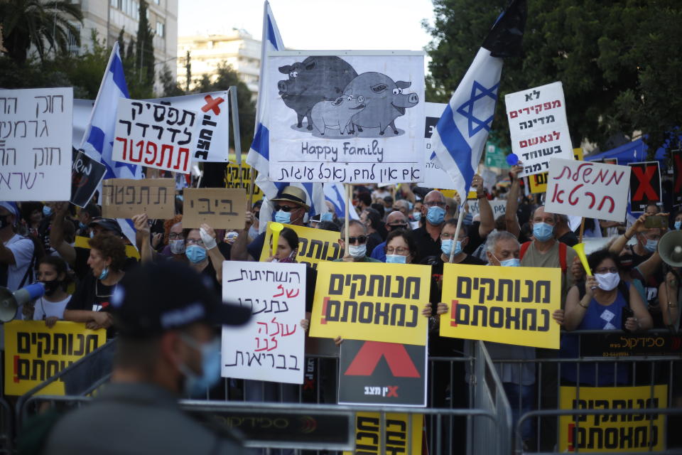 Protesters, defying orders to maintain social distancing requirements, chant slogans and blew horns outside of the Prime Minister's residence in Jerusalem, Tuesday, July 14, 2020. Thousands of Israelis demonstrated outside of the official residence of Benjamin Netanyahu, calling on the embattled Israeli leader to resign as he faces a trial on corruption charges and grapples with a deepening coronavirus crisis. The signs read: "you are detached. We are fed up." (AP Photo/Ariel Schalit)