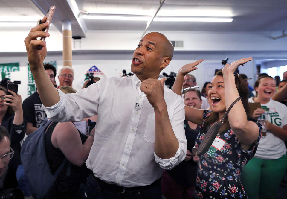 Booker records a video of himself using Celia Botto's phone as she cheers behind him during a campaign stop in Manchester, New Hampshire, on July 13. (Photo: Boston Globe via Getty Images)