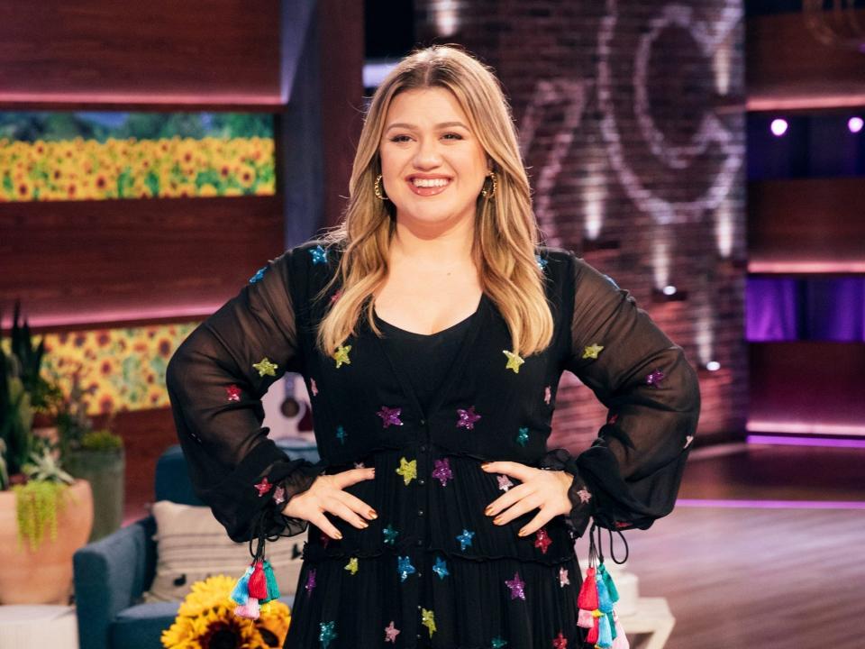 Kelly Clarkson in a black dress in her talk show studio.