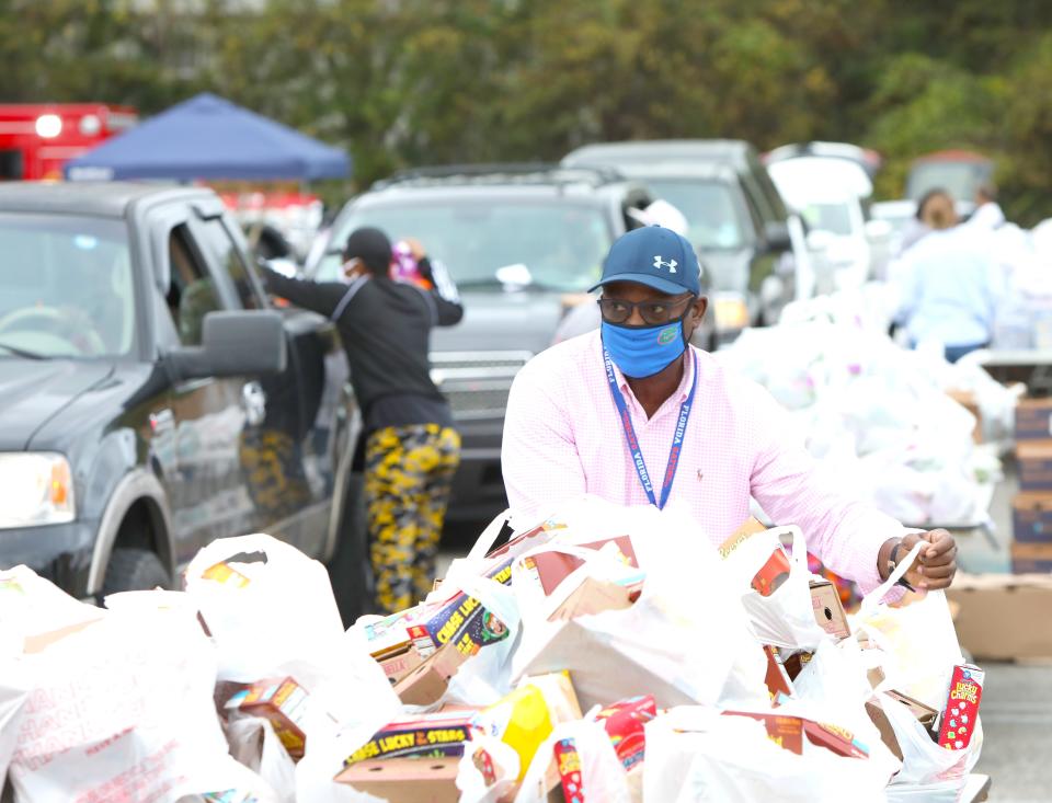 Volunteers give away bags of food during the Strike Out Hunger food drive in the parking lot at The Oaks Mall in Gainesville in 2021.
