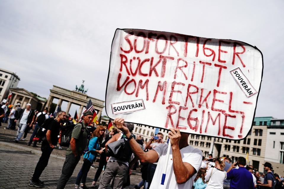 Ein Teilnehmer mit dem Plakat "Sofortiger Rücktritt vom Merkel-Regime!" steht vor einer Demonstration gegen die Corona-Maßnahmen am Brandenburger Tor.<span class="copyright">Kay Nietfeld / dpa</span>