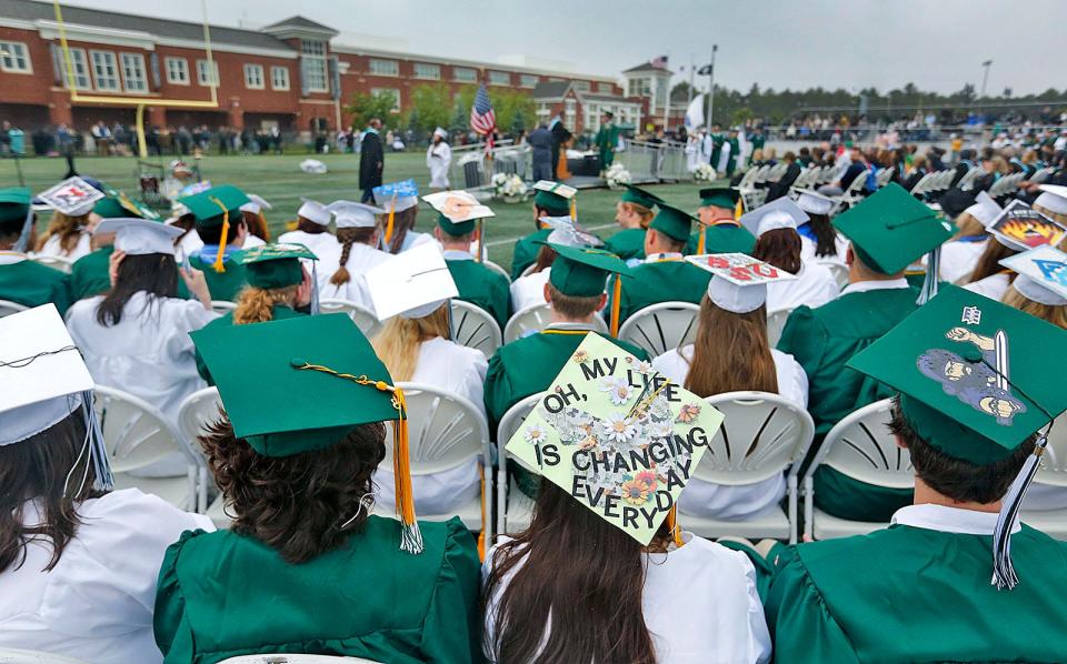 A graduate with a well-decorated cap waits to receive her diploma.