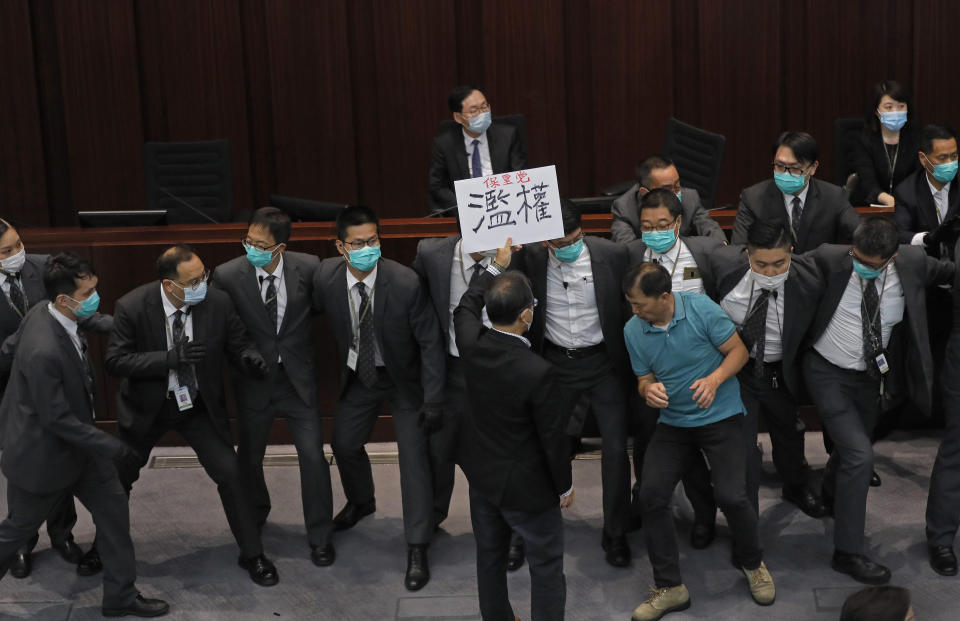 FILE - In this Monday, May 18, 2020, file photo, pro-democracy lawmaker Wu Chi-wai, right in green shirt, scuffles with security guards during a Legislative Council's House Committee meeting in Hong Kong. After nearly three decades in politics, the 58-year-old Wu, chairman of Hong Kong’s largest pro-democracy party, is stepping down Monday, Nov. 30, 2020. All 15 lawmakers in the pro-democracy camp have decided to resign to protest a Beijing resolution in early November that led to the disqualifications of four of their colleagues. (AP Photo/Vincent Yu, File)