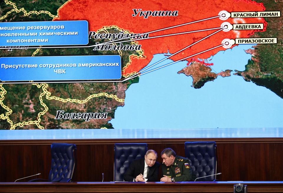 Russian President Vladimir Put, left, and Russian General Staff Valery Gerasimov talk to each other during an extended meeting of the Russian Defense Ministry Board at the National Defense Control Center with a Russian military map showing the alleged deployment of U.S. private military contractors in eastern Ukraine in the background in Moscow, Russia, Tuesday, Dec. 21, 2021. The Russian president on Tuesday reiterated the demand for guarantees from the U.S. and its allies that NATO will not expand eastward, blaming the West for current tensions in Europe. (Mikhail Tereshchenko, Sputnik, Kremlin Pool Photo via AP)