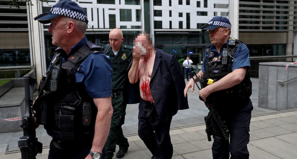 The man was flanked by armed cops and paramedics as he left the building. (Reuters)