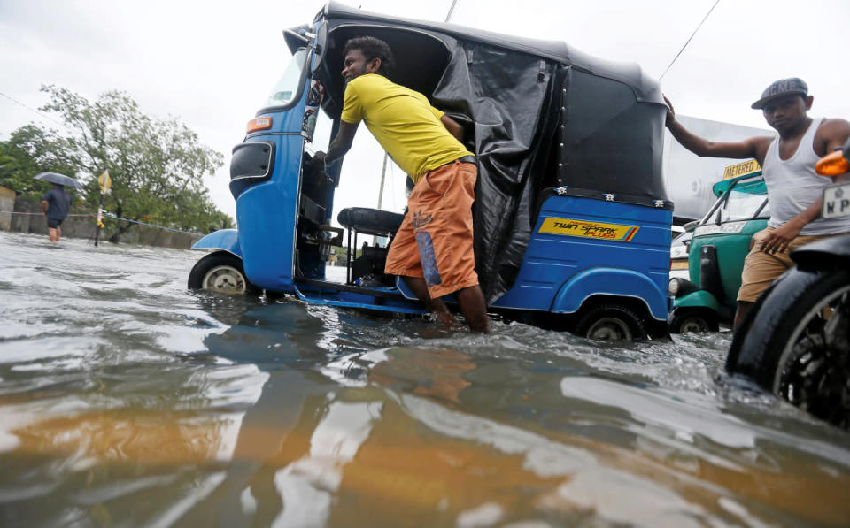 A man pushes his auto-rickshaw after it got stuck on a flooded road in Colombo, Sri Lanka, May 16, 2016. (Reuters/Dinuka Liyanawatte)