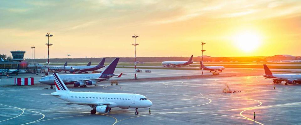 Airport with many airplanes on the tarmac at sunset.