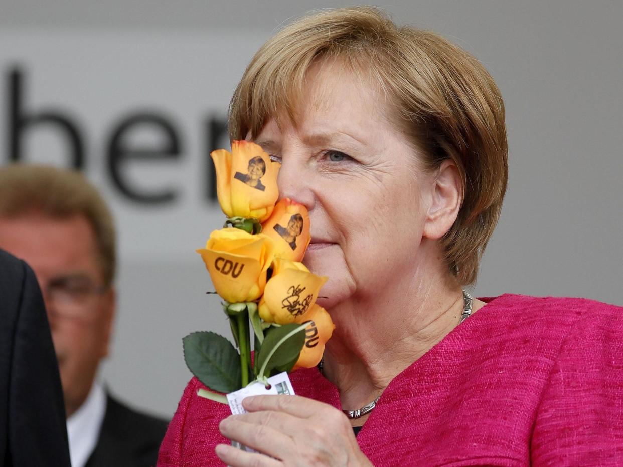 Angela Merkel smells some Christian Democratic Union (CDU) branded flowers at an election campaign event in Heppenheim: EPA