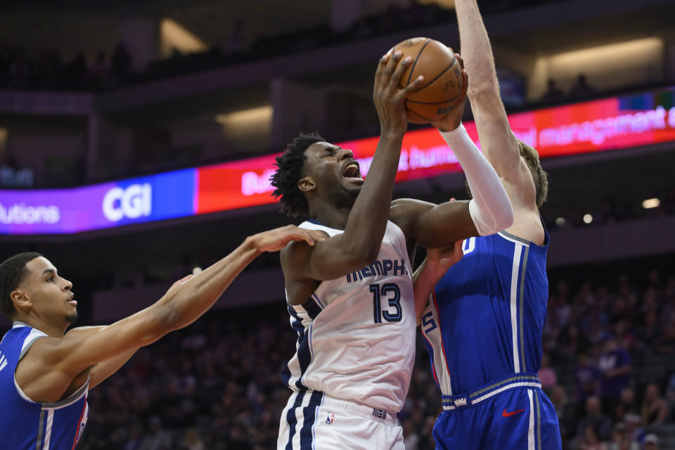 Memphis Grizzlies forward Jaren Jackson Jr. (13) drives to the basket past Sacramento Kings forwards Keegan Murray, left, and Domantas Sabonis, right, during the first half of an NBA basketball game in Sacramento, Calif., Monday, March 18, 2024. (AP Photo/Randall Benton)