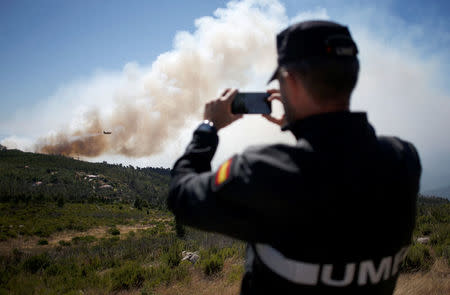 A firefighter films a plane as it drops water on a fire next to the village of Monchique, Portugal August 8, 2018. REUTERS/Pedro Nunes TPX IMAGES OF THE DAY