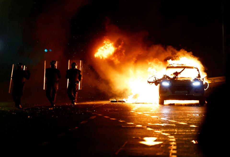 Riot police walks next to a burning police vehicle (REUTERS)