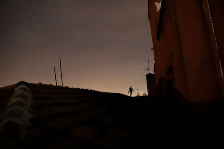 A "pichador", a graffiti artist who tags buildings and landmarks with angular, runic fonts, walks on the roof of a building as he carries an ink roller and a paint bucket before tagging a wall with his personal signature, called "pichacao", in Sao Paulo, Brazil, March 17, 2017. REUTERS/Nacho Doce