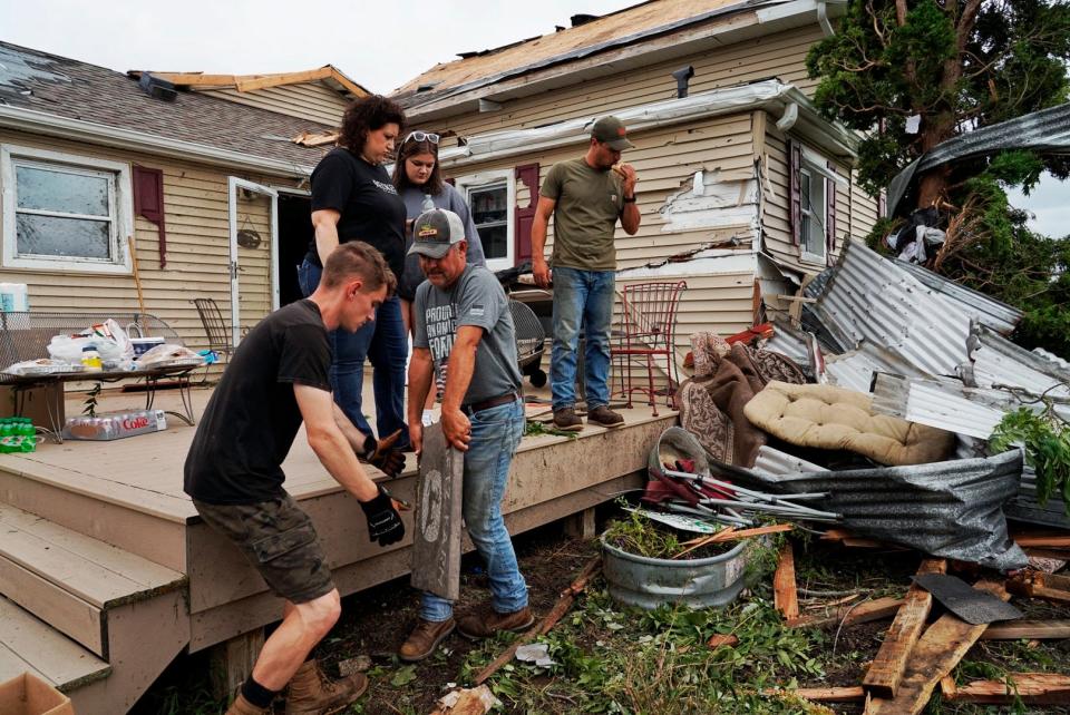 Nick Chema, left, of Perry helps his father-in-law Timothy Dietz move a placard while cleaning up his property in Williamston that was damaged by a tornado on Friday, August 25, 2023, taking out three barns including one that was built 190 years ago on his families farm named Dietz Farm. Dietz said as soon as he swiped away the alert on his phone the tornado pulled glass from the windows and ripped the garage off the house. “We’re in shock. It’s something our family has taken pride in for years,” said Dietz about the farm. “We lose a little bit of history.” Chema also said he and his wife recently had a tornado come by their house in Perry a couple weeks ago and we’re now on hand to help their family with the damage from the tornado in Williamston.