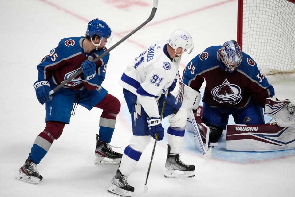 Tampa Bay Lightning center Steven Stamkos, center, puts a shot on Colorado Avalanche goaltender Darcy Kuemper, right, after slipping past Avalanche left wing Andre Burakovsky during the third period of an NHL hockey game Thursday, Feb. 10, 2022, in Denver. The Avalanche won 3-2. (AP Photo/David Zalubowski)