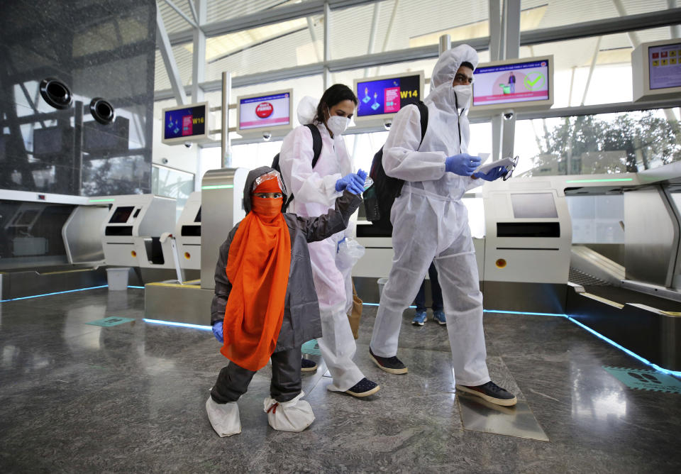 Una familia con trajes de protección en una aeropuerto de la India. (AP Photo/Aijaz Rahi)