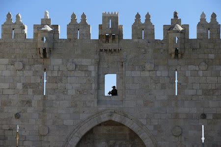 An Israeli border policeman holds his weapon as he guards the area from above while his comrades patrol at Damascus Gate in Jerusalem's Old City February 17, 2016. REUTERS/Ammar Awad