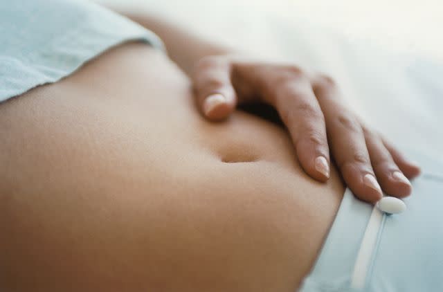 Getty Images/Laurence Monneret Stock image of woman with hand on her stomach