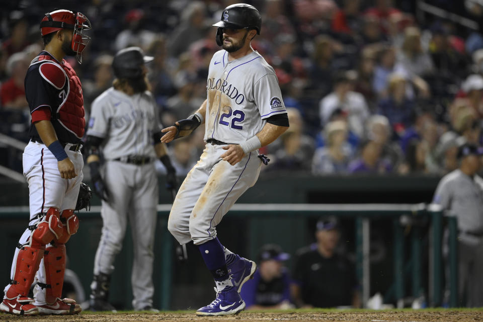 Colorado Rockies' Sam Hilliard (22) comes in to score on a single by Brendan Rodgers during the ninth inning of a baseball game against the Washington Nationals, Friday, Sept. 17, 2021, in Washington. Nationals catcher Keibert Ruiz, left, looks on. (AP Photo/Nick Wass)