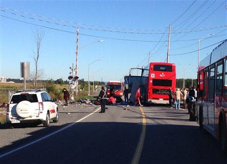 Handout photo of bystanders standing around the scene where a Via Rail train collided with a double-decker bus in Ottawa