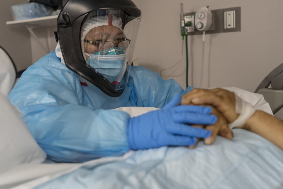 HOUSTON, TX - DECEMBER 6: (EDITORS NOTE: Image depicts death.) (EDITORIAL USE ONLY) A medical staff member Susan Paradela pauses for a moment as she places her hands on a a deceased patient's hands before put the patient into a body bag in the COVID-19 intensive care unit (ICU) at the United Memorial Medical Center on December 6, 2020 in Houston, Texas. According to reports, Texas has reached over 1,330,000 cases, including over 23,100 deaths. (Photo by Go Nakamura/Getty Images)