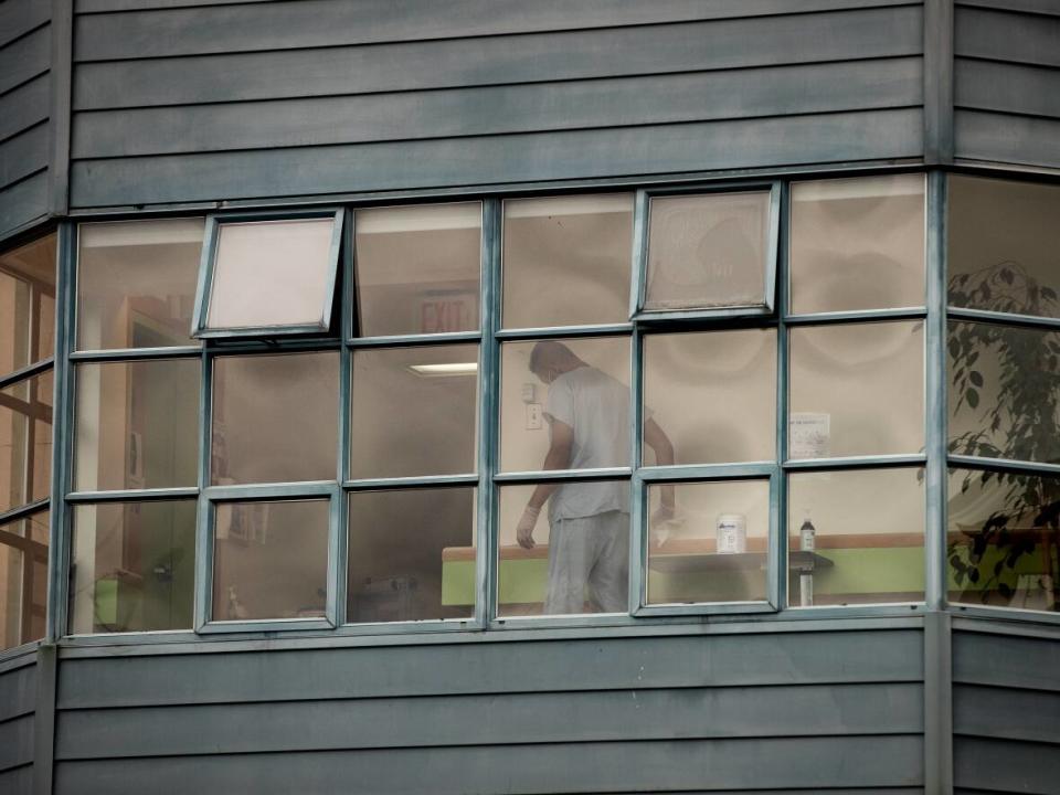 A worker is seen cleaning surfaces inside Little Mountain Place, a long-term care home where 41 residents died during a COVID-19 outbreak declared in November 2020. (Darryl Dyck/The Canadian Press - image credit)