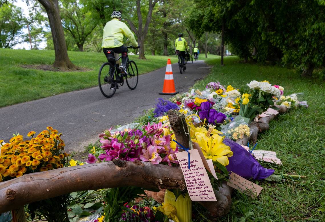 A cyclist rides past a memorial of flowers on Wednesday, May 3, 2023, marking the location that Karim Abou Najm, a graduating senior at UC Davis, was stabbed Saturday in Sycamore Park in Davis. It was the second of three stabbings, two fatal, in the city in less than a week.