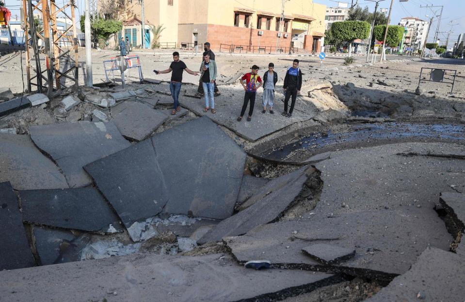 Palestinian youths take pictures with their smart phones of a huge crater on a main road in Gaza CityAFP via Getty Images