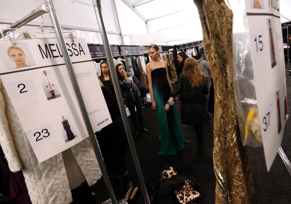 A model has her dress worked on backstage before the Monique Lhuillier Fall 2013 collection is modeled during Fashion Week, Saturday, Feb. 9, 2013 in New York. (AP Photo/Jason DeCrow)