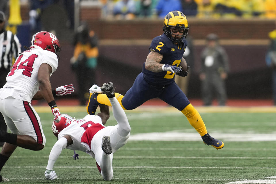 Michigan running back Blake Corum (2) evades the tackle of Indiana defensive back Kobee Minor (5) as Aaron Casey (44) pursues in the first half of an NCAA college football game in Ann Arbor, Mich., Saturday, Oct. 14, 2023. (AP Photo/Paul Sancya)