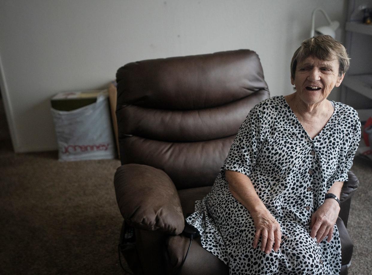 Sue Smith relaxes in her sparsely furnished home. Smith grew up not knowing that she had hearing loss. She wants help connecting to services and accessibility items.