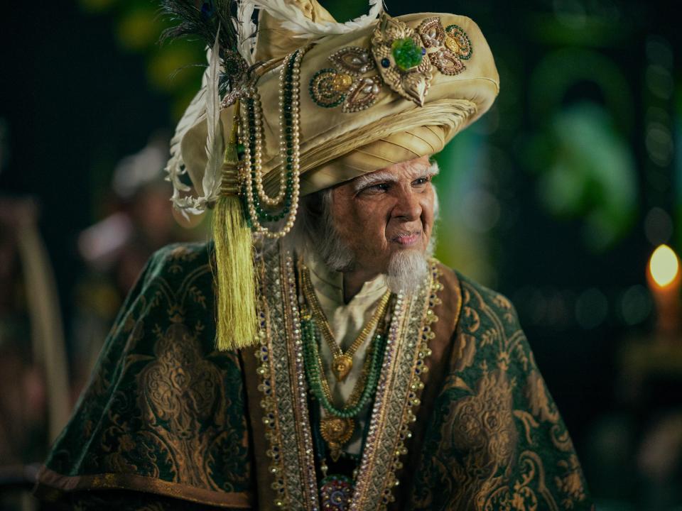 bumi in avatar the last airbender live action, wearing an ornate fabric headpiece and green robes