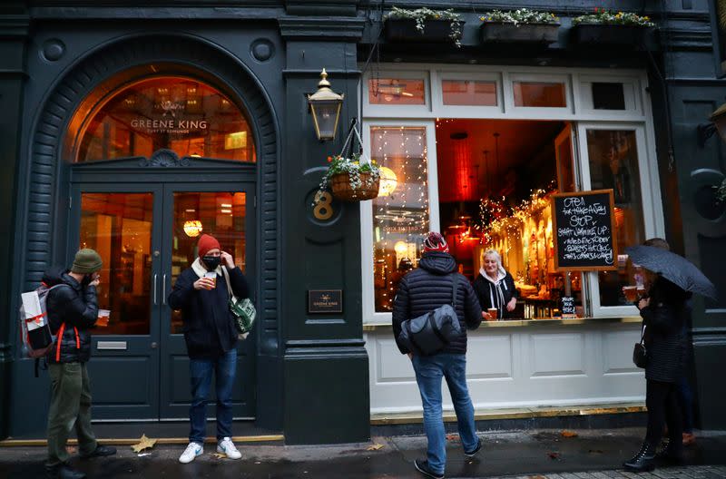 FILE PHOTO: People drink outside a pub that is open for takeaway drinks in London