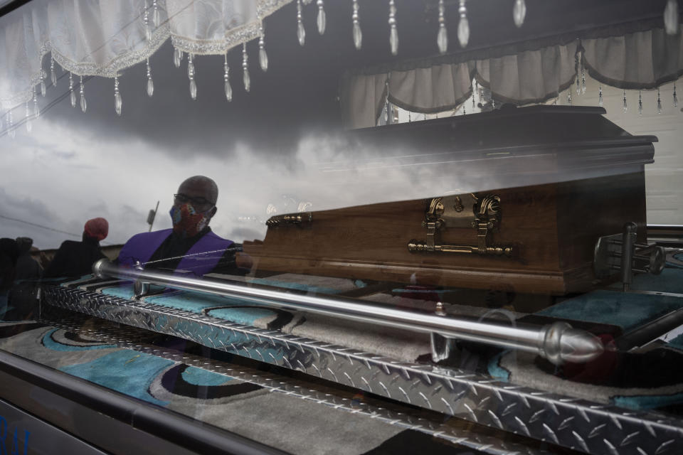 A funeral worker is reflected in the window of the car that carries 5-year-old Wandi Zitho's coffin in Orange Farm, South Africa, on April 28, 2020. The neighbor originally charged with killing the boy was released and the case provisionally dropped because the police didn’t deliver enough evidence. Months later, the woman was arrested again and charged with murdering two other children. (AP Photo/Bram Janssen)