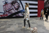 A woman walks her dog in a retail district in Beijing on Thursday, April 15, 2021. China’s economic growth surged to 18.3% over a year earlier in the first quarter of this year as factory and consumer activity recovered from the coronavirus pandemic. (AP Photo/Ng Han Guan)