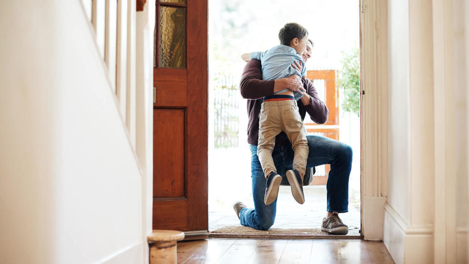 Shot of a little boy running into his father's arms as he arrives at home.