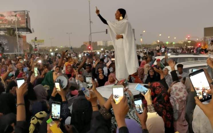 Around half the Khartoum protesters are reportedly women, including Alaa Saleh, 22, pictured addressing the crowd on top of a car - LANA H. HAROUN