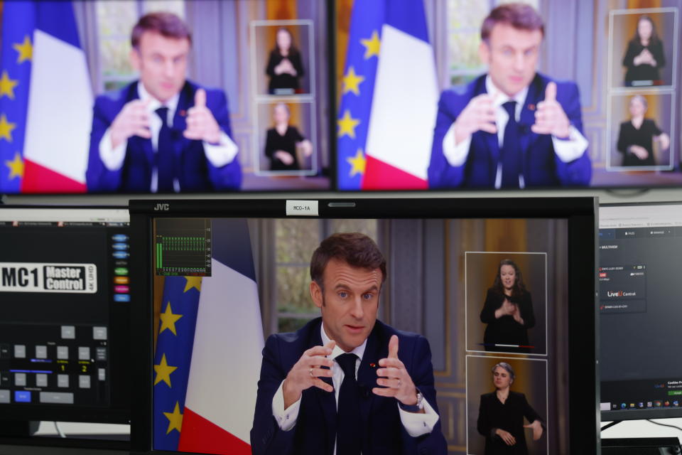 French President Emmanuel Macron is seen on screens as he speaks during a TV interview from the Elysee Palace, in Paris, on March 22, 2023.