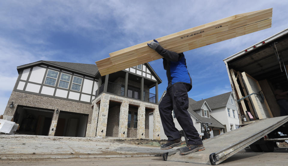 A worker carries interior doors to install in a just completed new home in north Dallas.  (LM Otero, AP Photo)