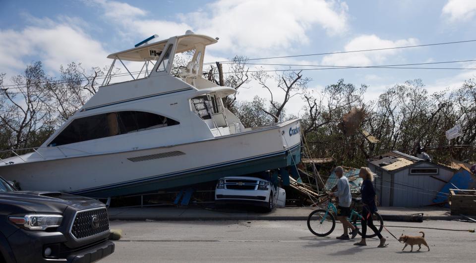 People walk along past damage along San Carlos Boulevard on the way to Fort Myers Beach on Thursday. Hurricane Ian made landfall near the area and devastated the area. 