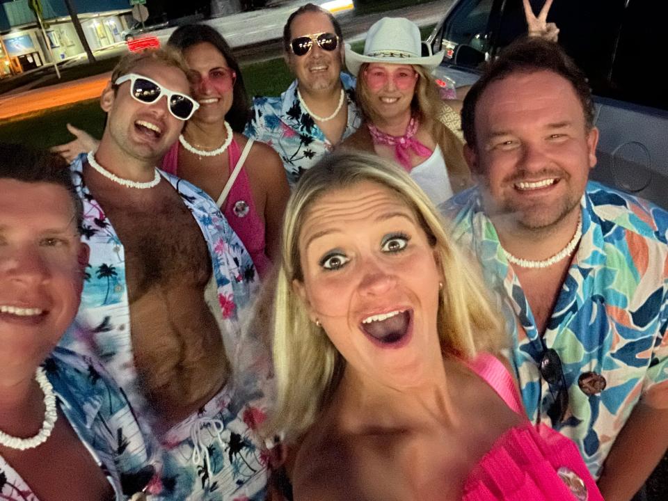 Selfie of Terri Peters and her friends dressed in their Barbie outfits while outside. Behind them is a dark sky and parking lot