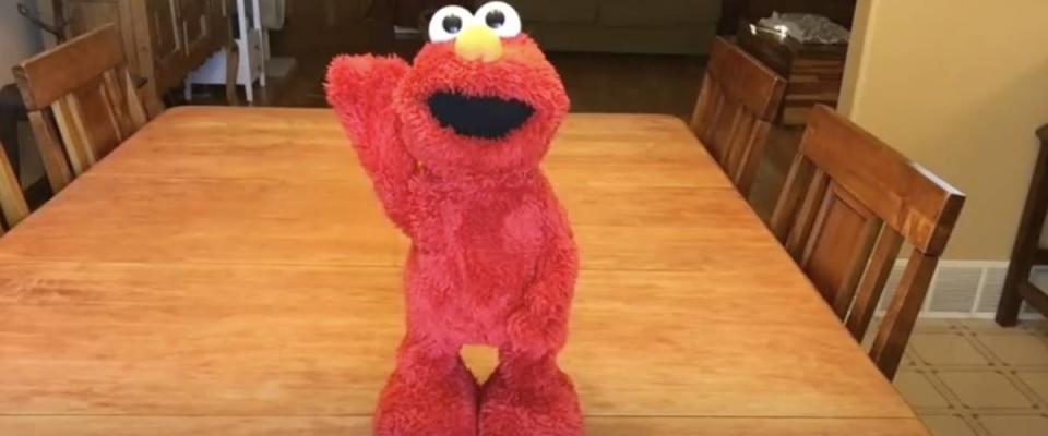 Elmo doll standing on a wooden table