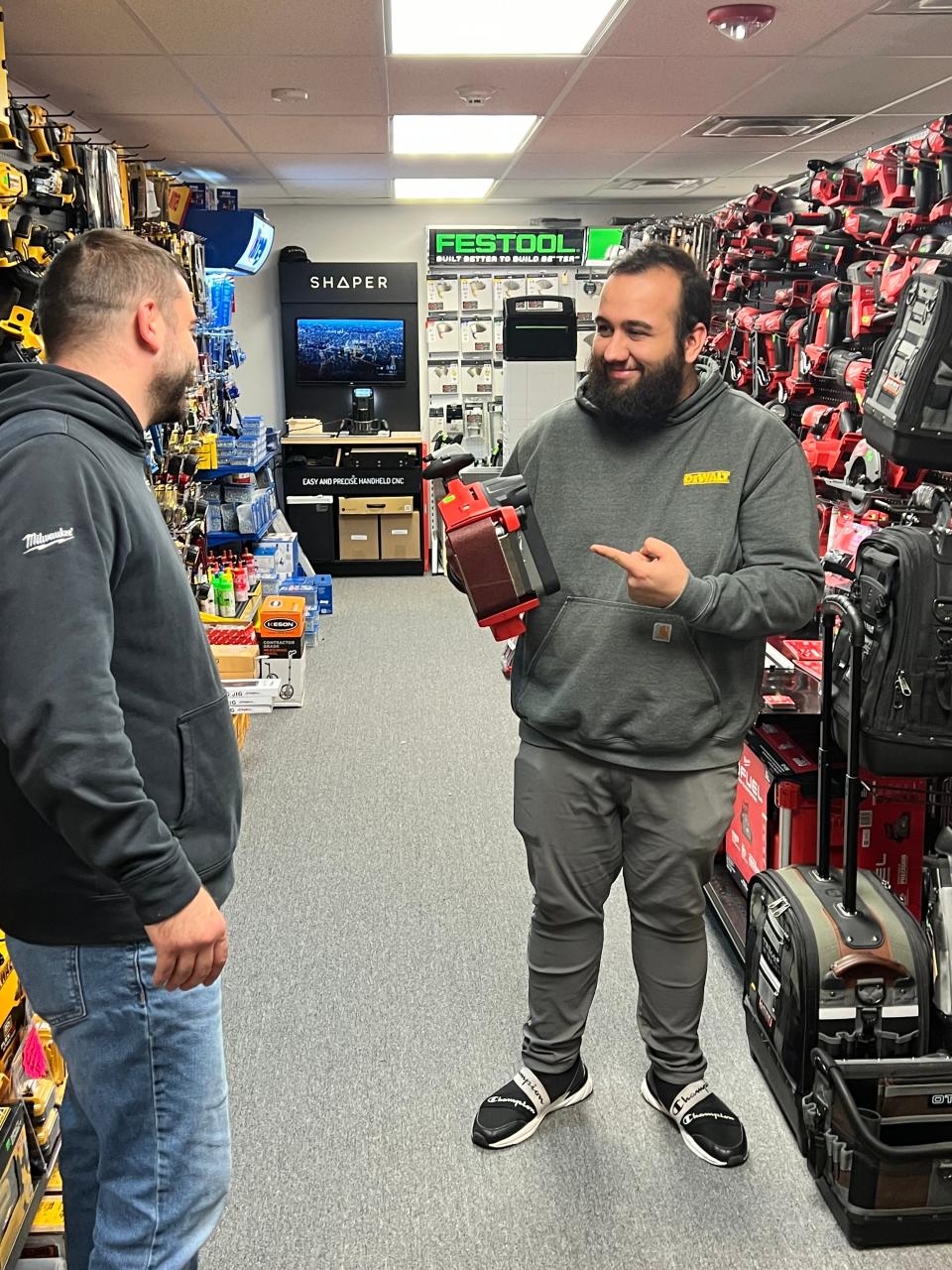 Rich Nolan, left, and Josh Rebello, holding a Milwaukee cordless belt sander, talk about gift options at Burns Power Tools in Tiverton.