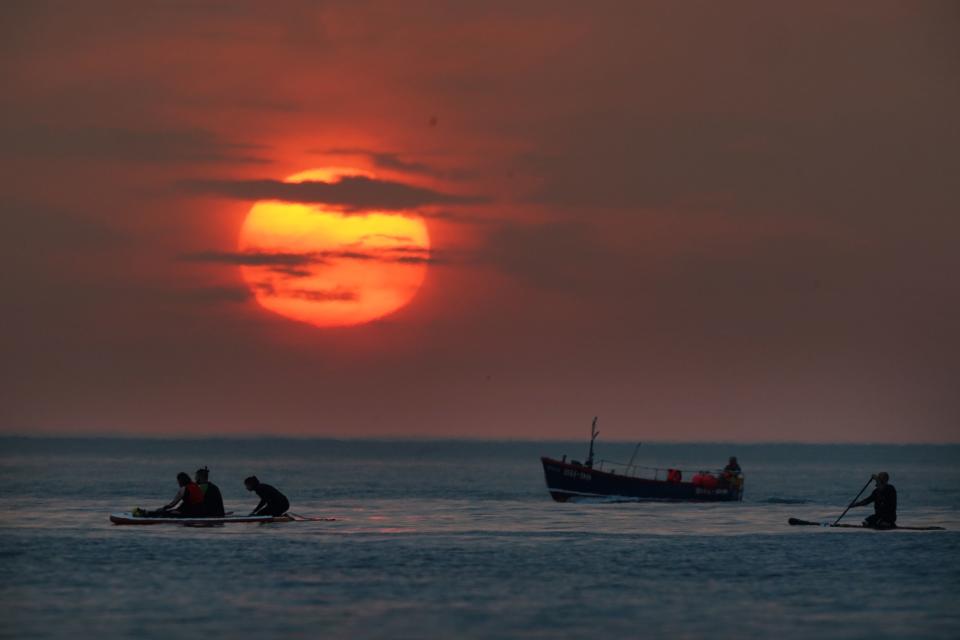 People turn out to watch the sunrise at Cullercoats Bay, North Tyneside (PA)