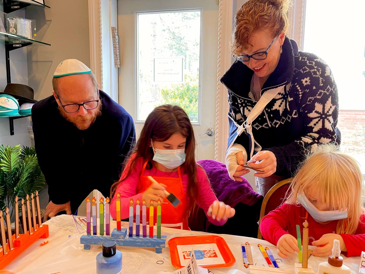 Dover parents Andrew Lael and Shara Zoll watch as Laela Zoll, 8, and Eleana Zoll, 4, create wooden menorahs on Sunday, Nov. 21, 2021, at the Seacoast Jewish Center in Durham.