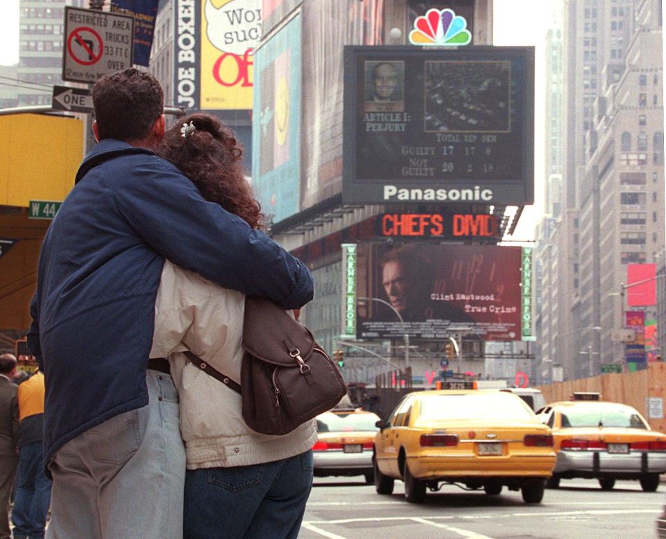 A couple watches the NBC jumbotron in Times Square display the "Not Guilty" verdict on the Obstruction of Justice charges against President Bill Clinton during his impeachment trial on Capitol Hill  February 12, 1999.  (Photo: Timothy A. Clary/AFP via Getty Images)